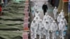 Market workers wearing protective gear spray disinfectant at a market in the southeastern city of Daegu on February 23, 2020 as a preventive measure after the COVID-19 coronavirus outbreak.